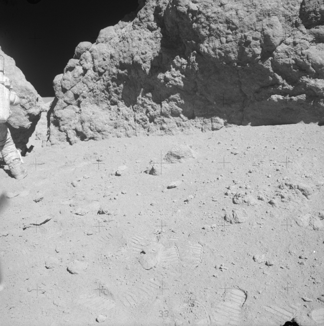 Handheld image taken by Duke showing Young near the smaller attached boulder "outhouse" rock and "House" rock on the right. Apollo image AS16-106-17354 [NASA]
