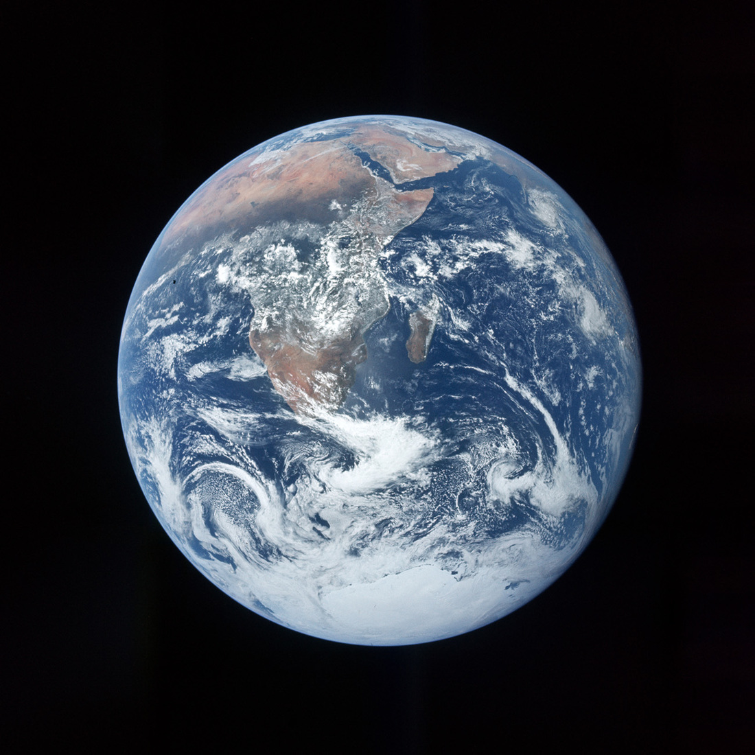 Image of Earth centered on south african coastlines with swirling clouds layered on top and collecting around Antarctica and the south pole; taken by the Apollo 17 crew during lunar transit.